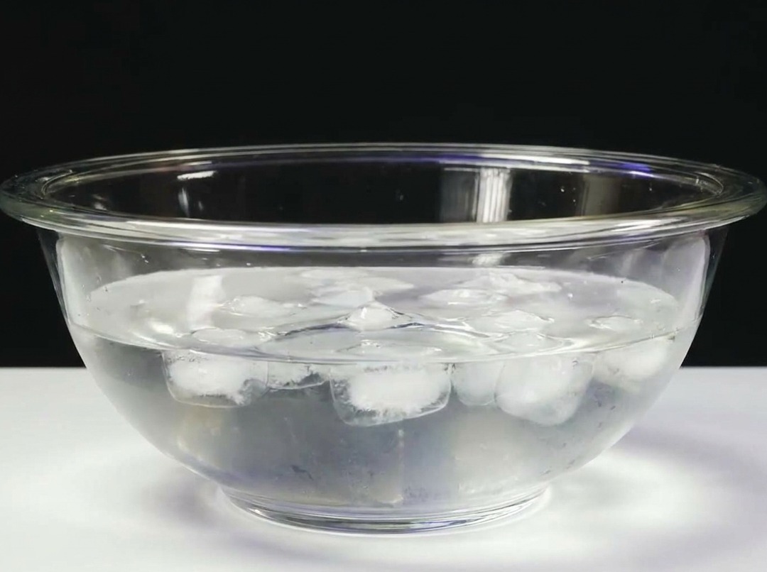 Un bloque de atún sumergido en un bol de cristal lleno de agua helada.
