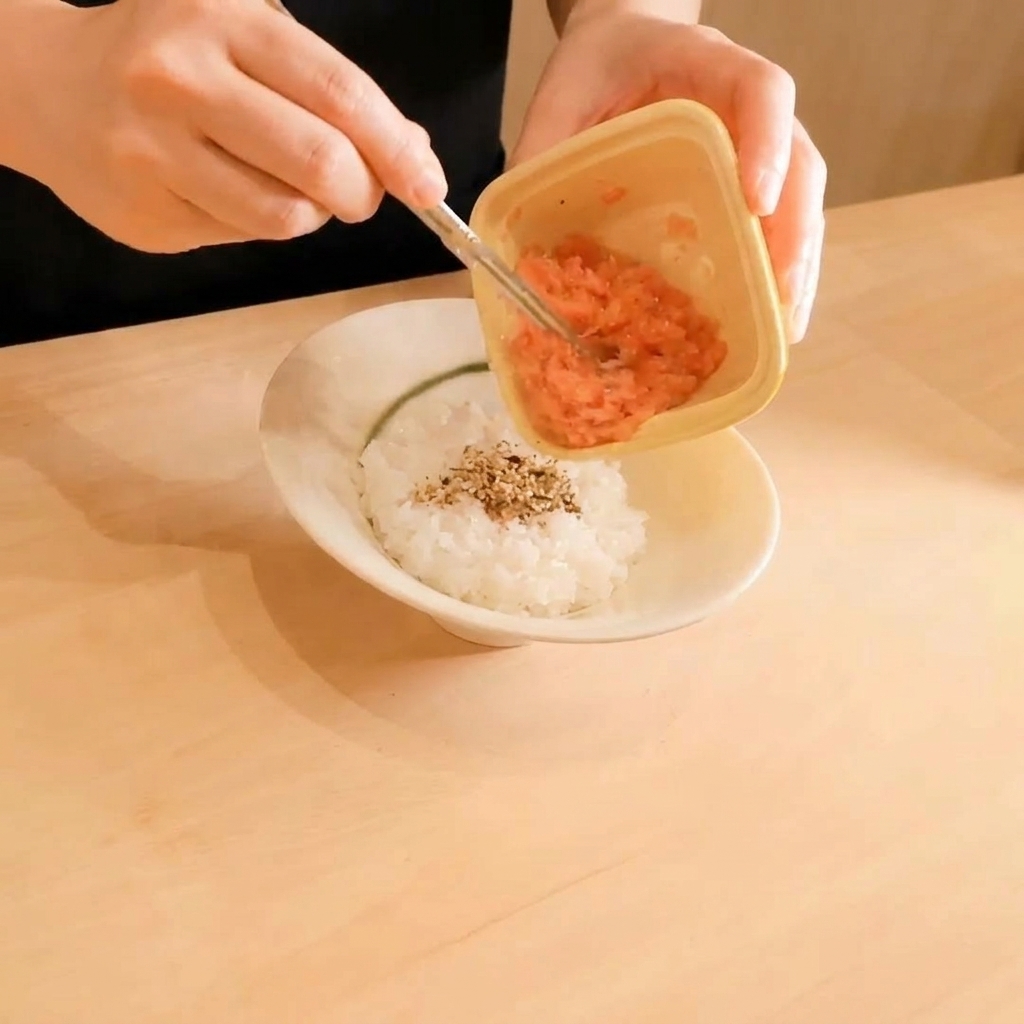 Atún crudo picado siendo colocado sobre una cama de arroz con semillas de sésamo.