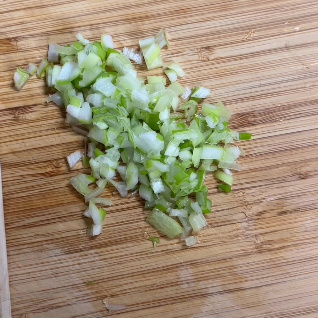 Cebolleta fresca siendo picada finamente sobre una superficie de madera.