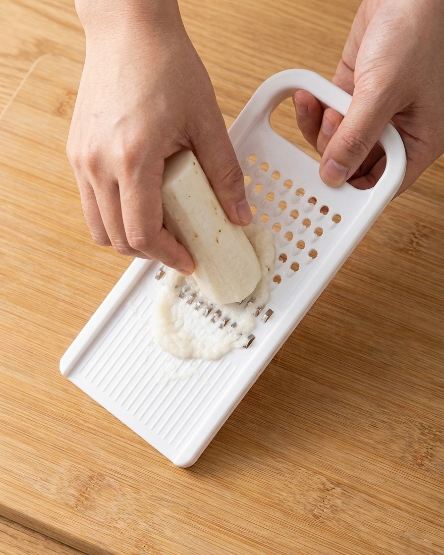 Pasta de ñame chino blanco recién rallado recolectada de un rallador de plástico.