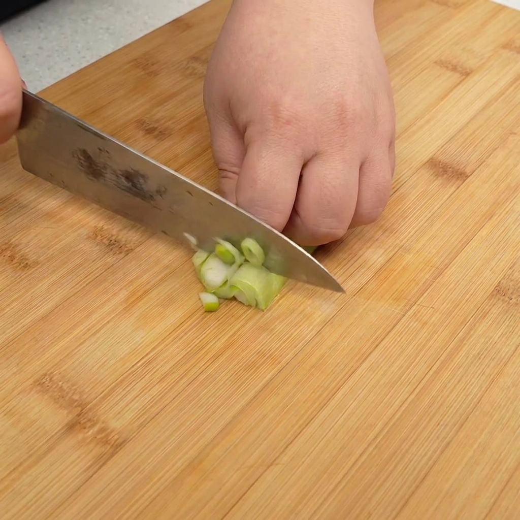 Cebolleta picada finamente sobre una tabla de madera.