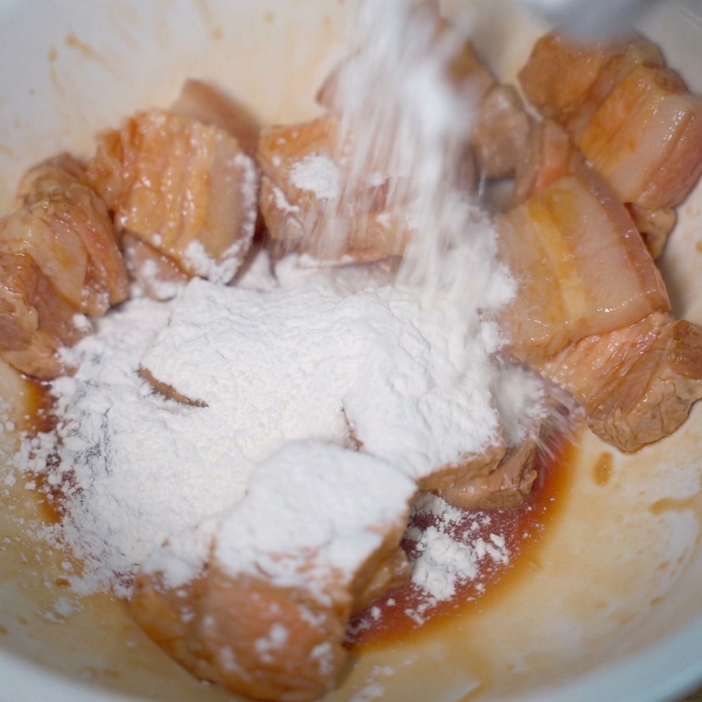 Trozos de panceta en un cuenco espolvoreados con una capa de almidón de tapioca.