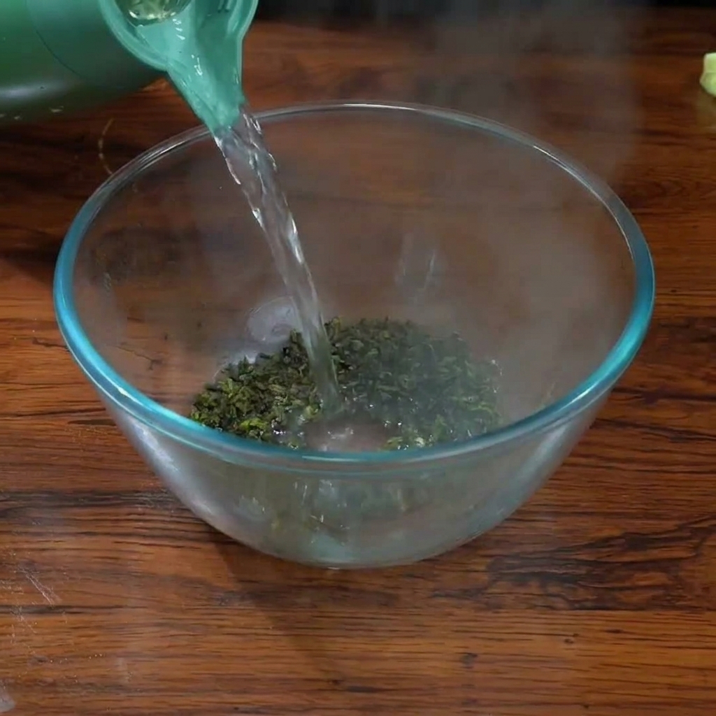Vertiendo agua hirviendo de un hervidor verde sobre hojas de té Tieguanyin en un bol de cristal transparente.