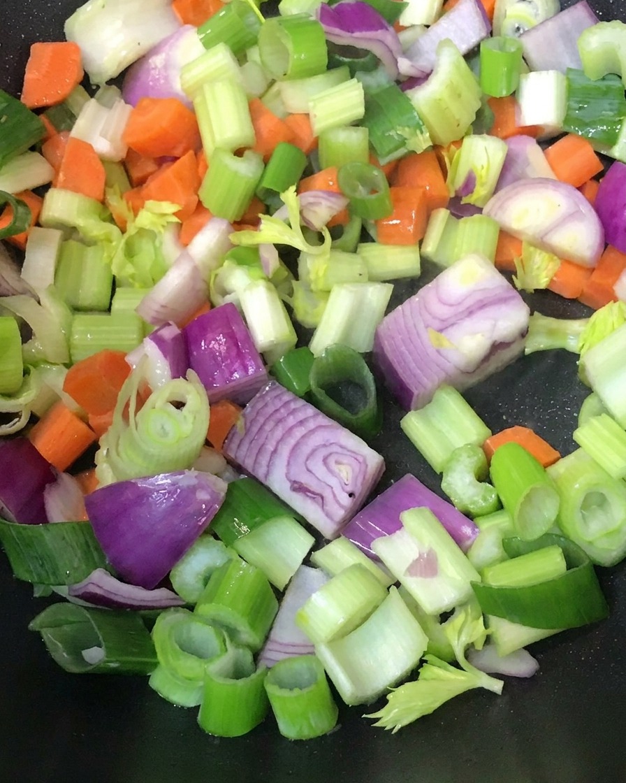 Verduras picadas salteándose en una sartén caliente.