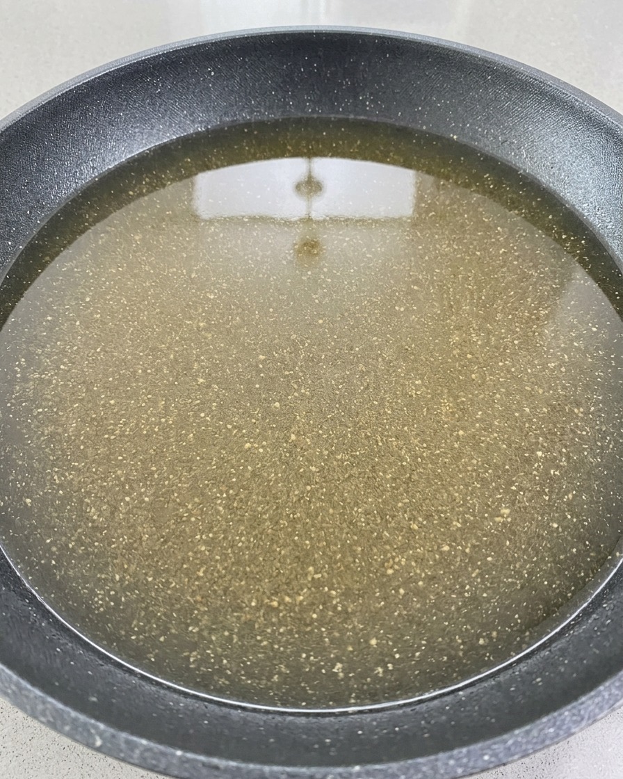 Vino tinto siendo vertido sobre la base de carne y verduras en una olla.