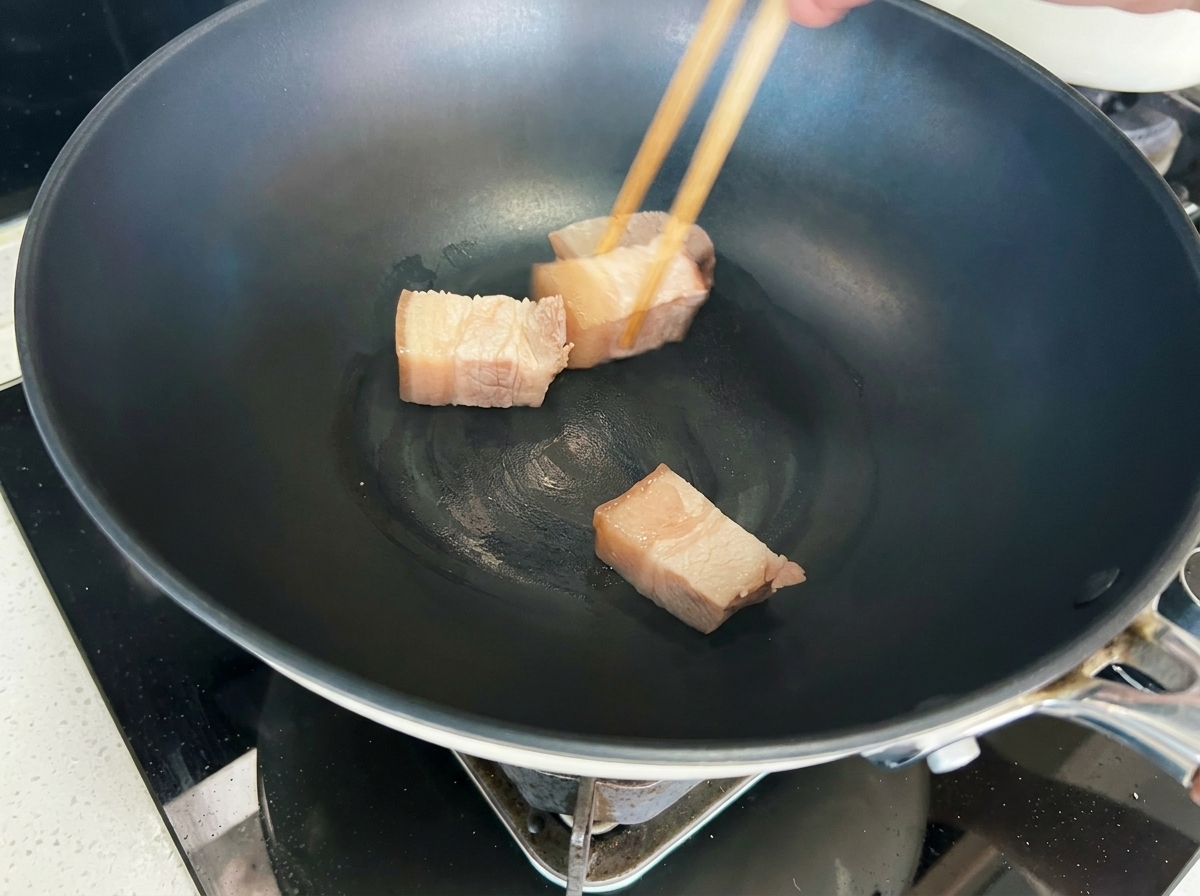 Dados de cerdo dorándose en un wok hasta adquirir un color marrón dorado.