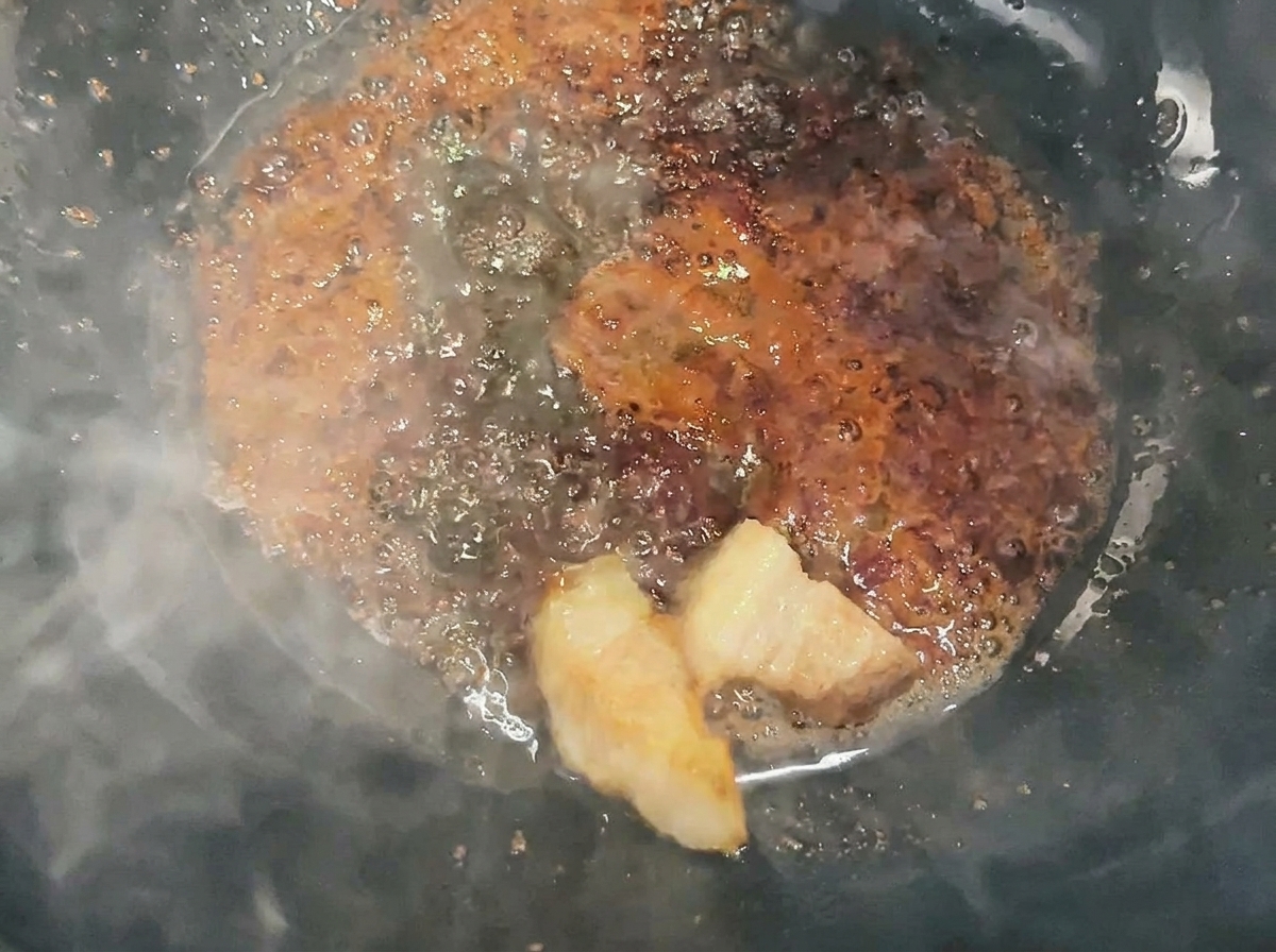 Dados de cerdo siendo salteados y cubiertos con caramelo líquido en un wok.