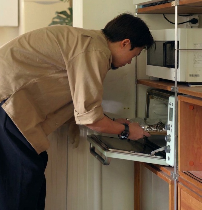 Una persona colocando una bandeja de costillas envueltas en papel aluminio dentro de un horno para su cocción lenta.