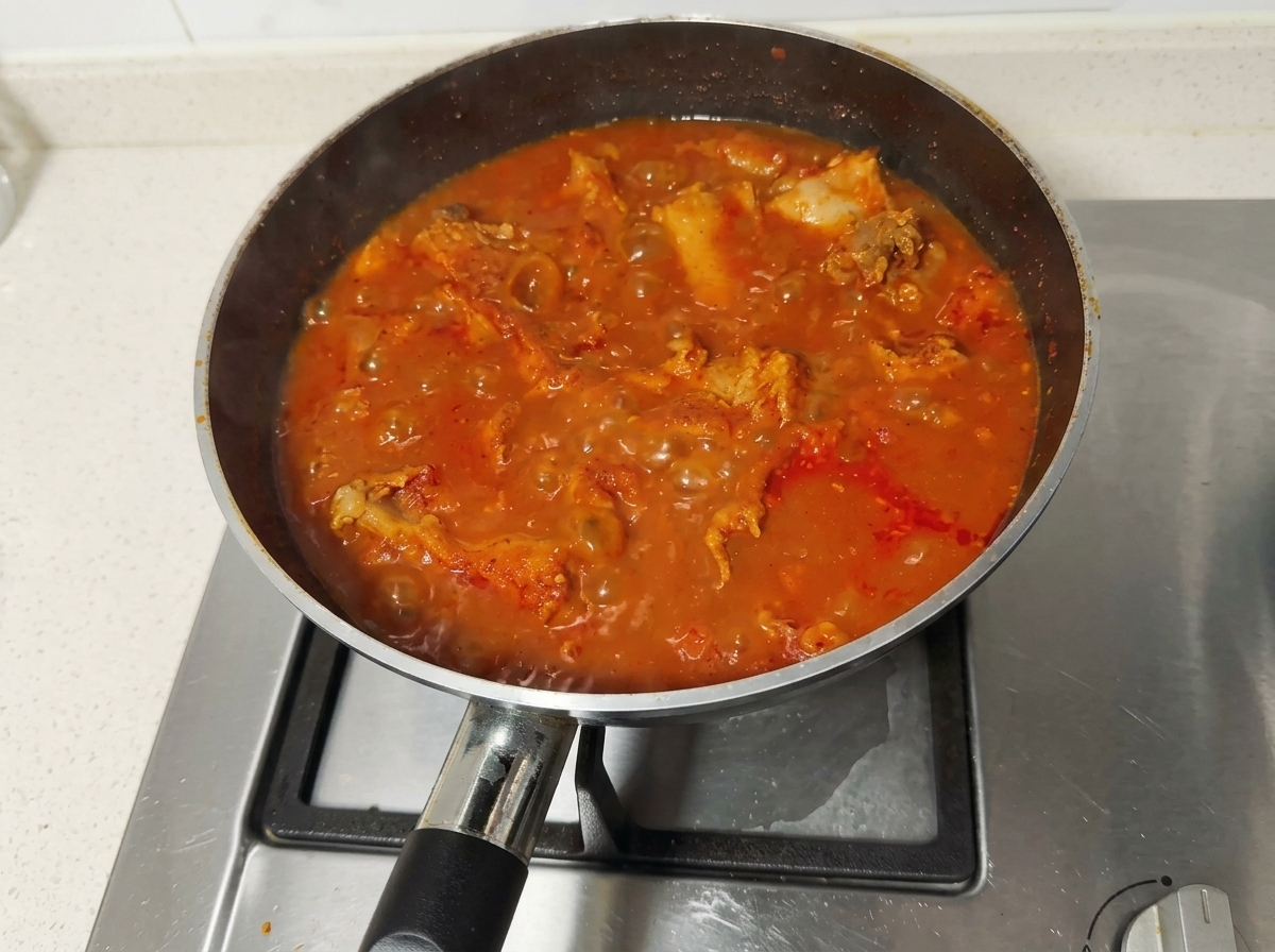 Estofado de costillas de cerdo con chile rojo hirviendo vigorosamente en una sartén.