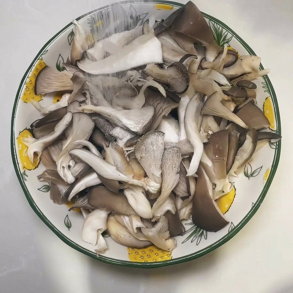 Un bol lleno de setas ostra crudas y deshechas siendo espolvoreadas con sal.