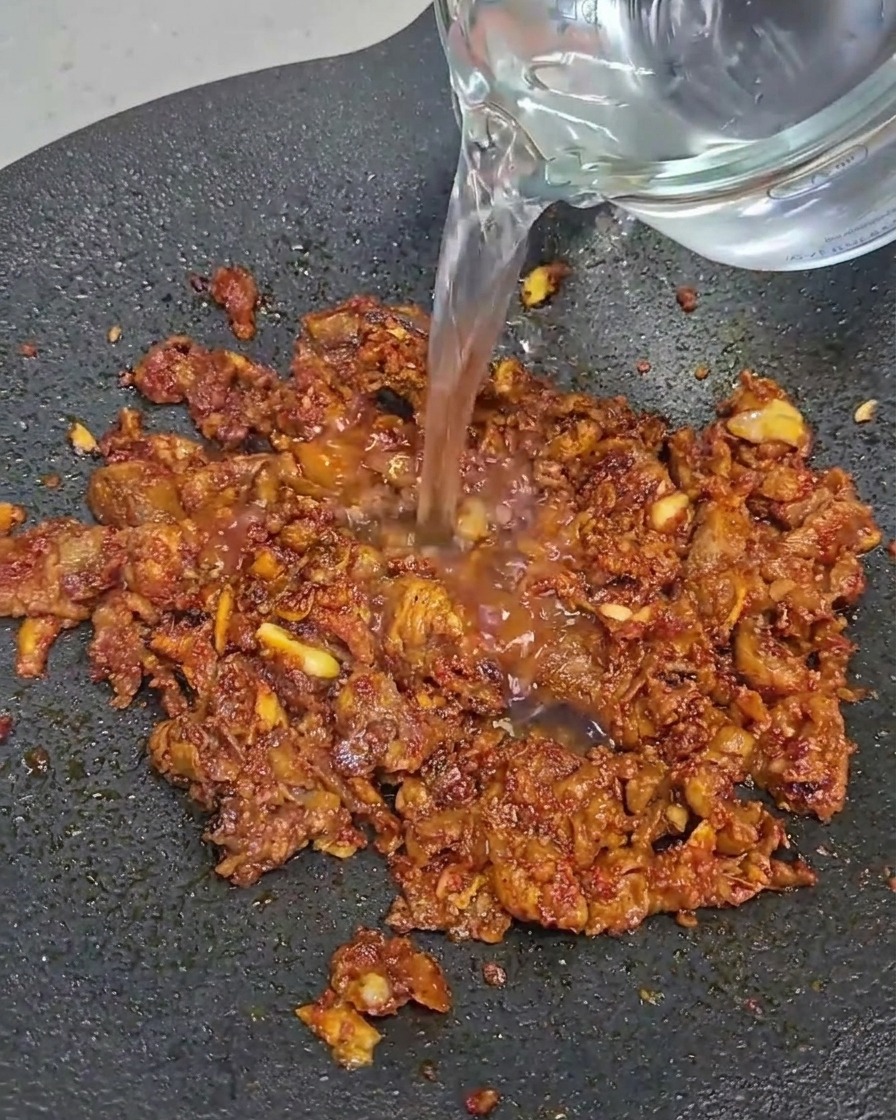 Láminas de panceta de ternera cocinándose en una sartén negra.