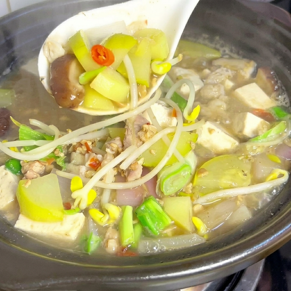 Gajos de calabacín y rodajas de champiñones shiitake dejándose caer en una olla de caldo burbujeante.