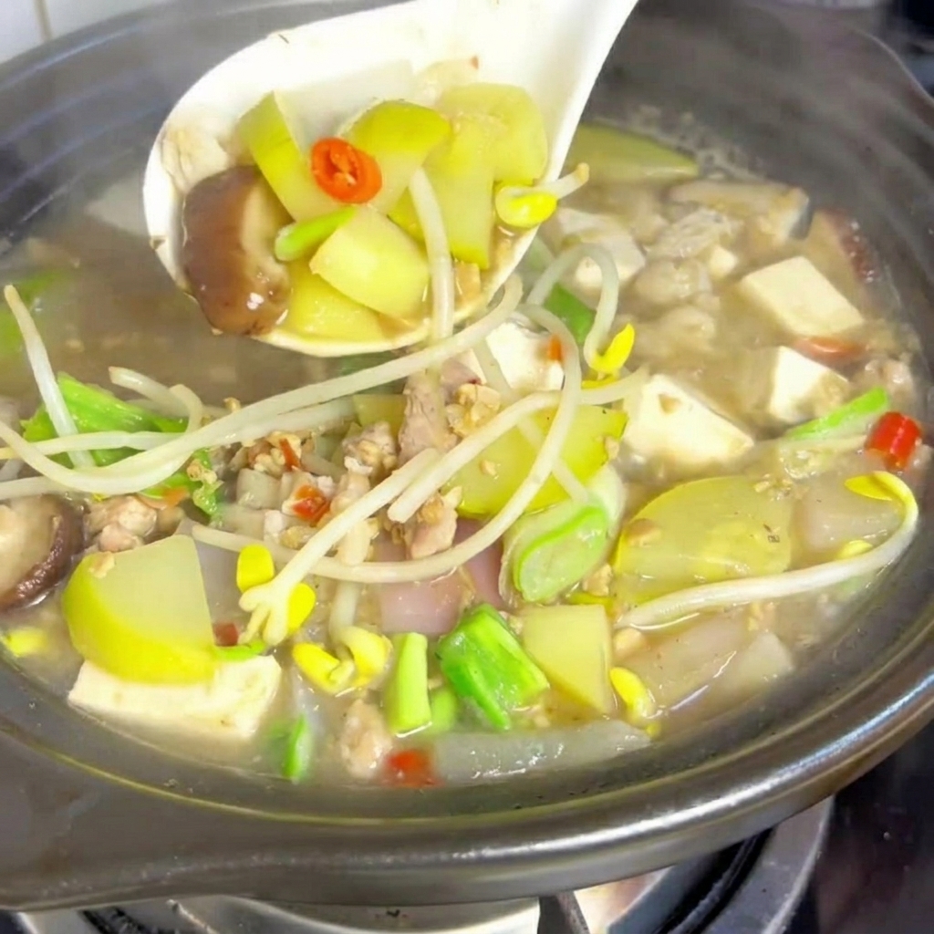 Cubos de tofu suave colocándose en la olla de estofado hirviendo a fuego lento.