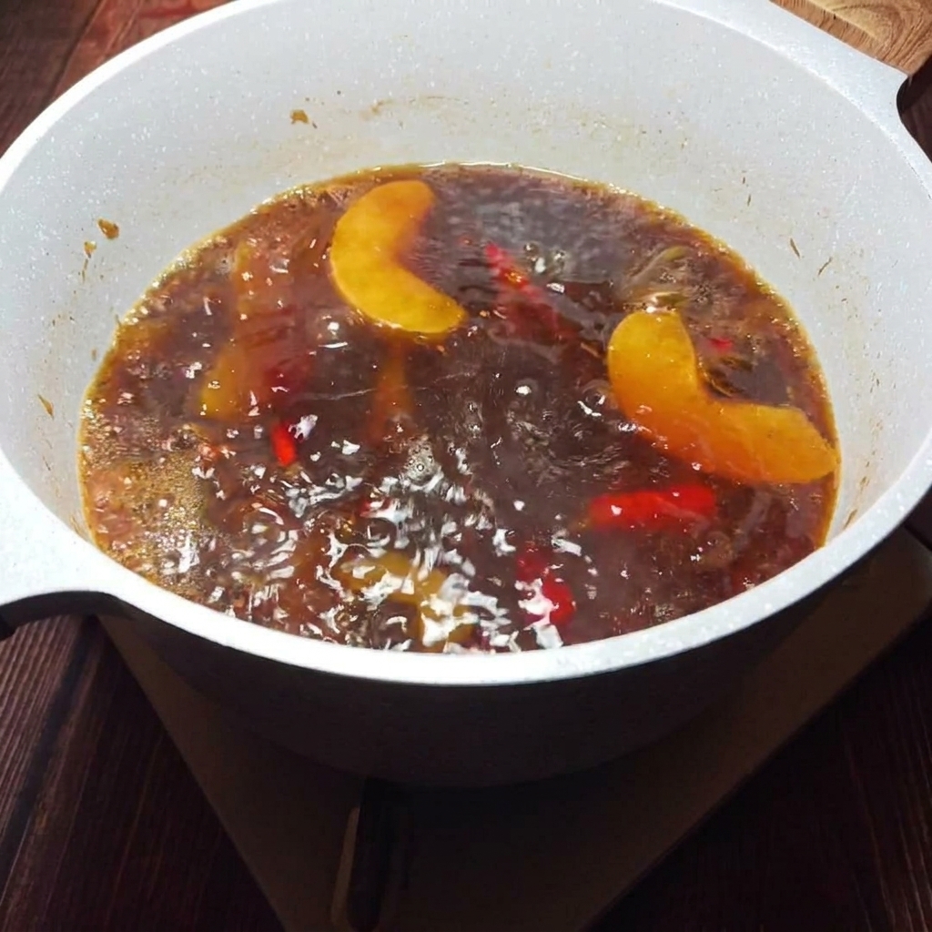 Un caldo dorado y aromático colándose a través de un tamiz para retirar los sólidos.