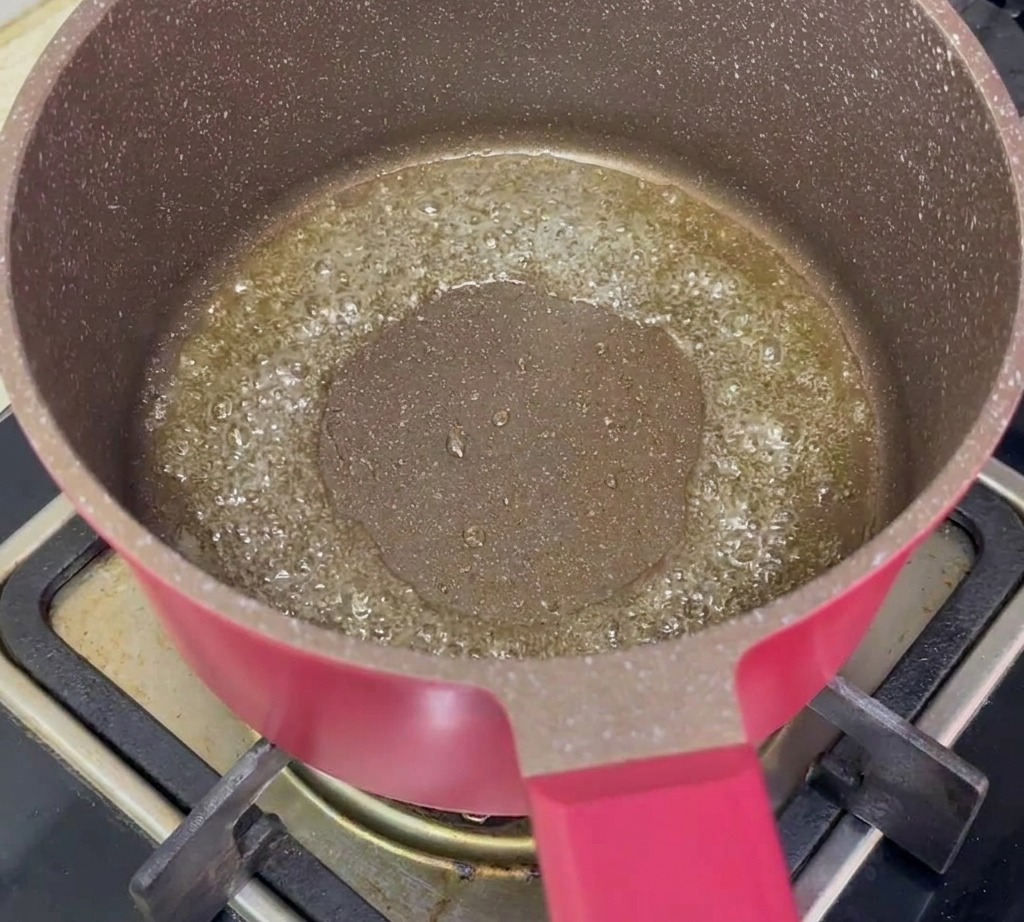 Zanahorias cortadas y cebollino picado sofriéndose en una sartén con aceite caliente.