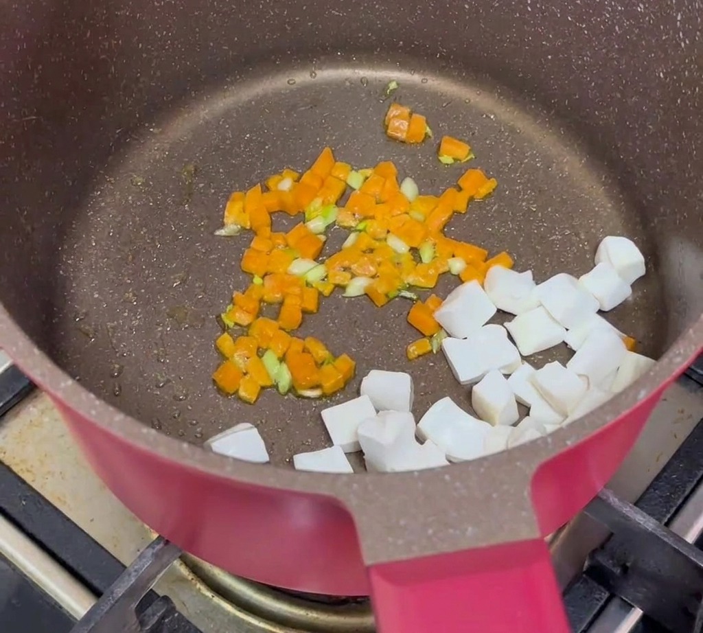 Cubos de tofu, carne picada cocinada y zanahorias sofritas combinados en una sartén.