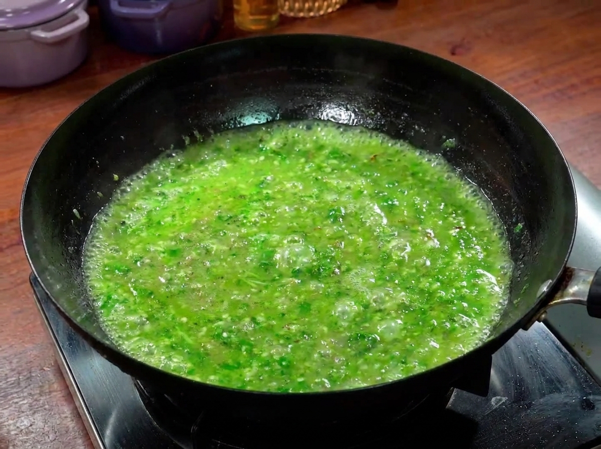 Láminas de ternera cocinándose en un caldo verde especiado burbujeante dentro de un wok.