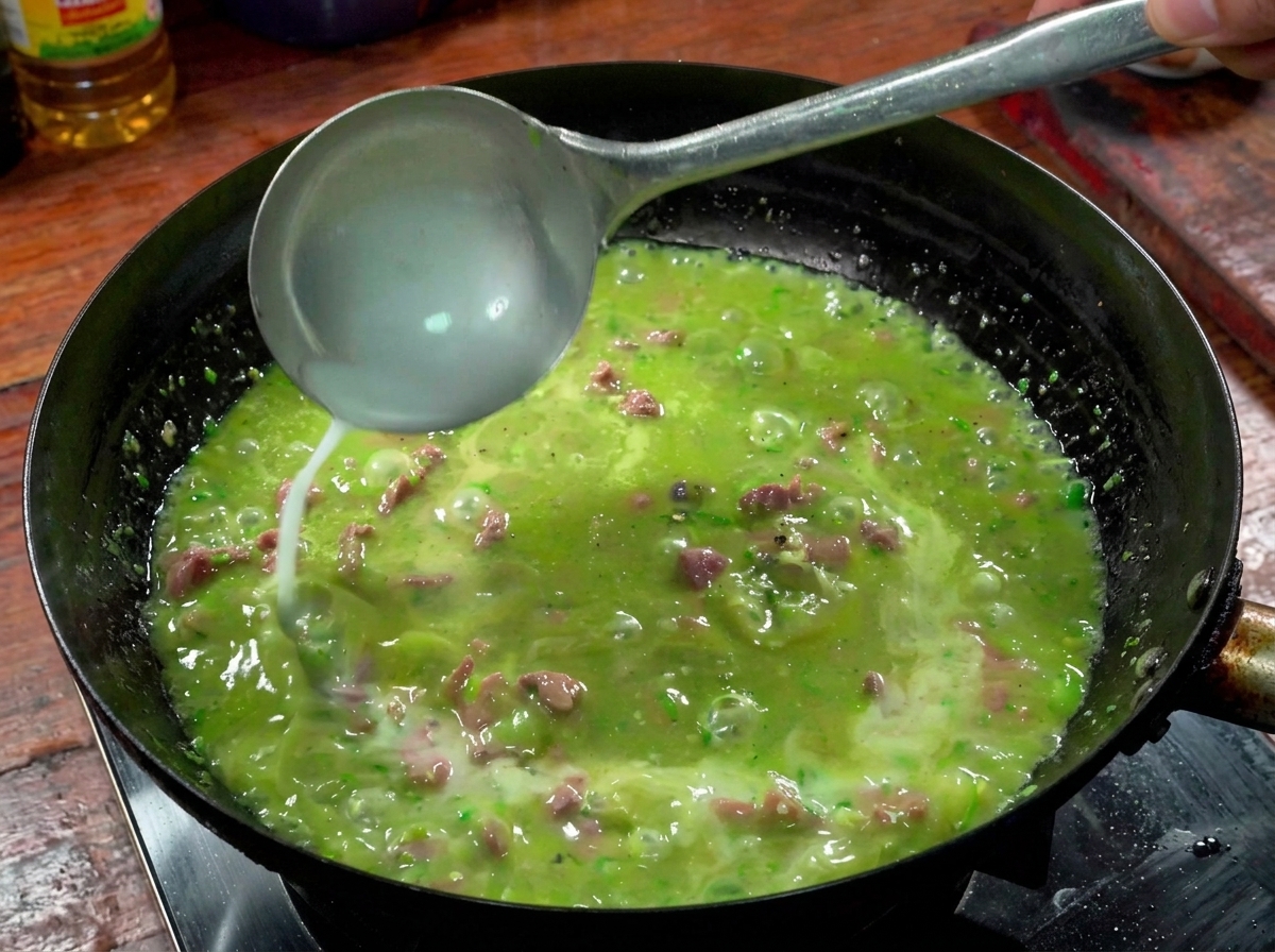 Un cucharón vertiendo agua con almidón en la salsa de ternera y chile burbujeando en el wok.