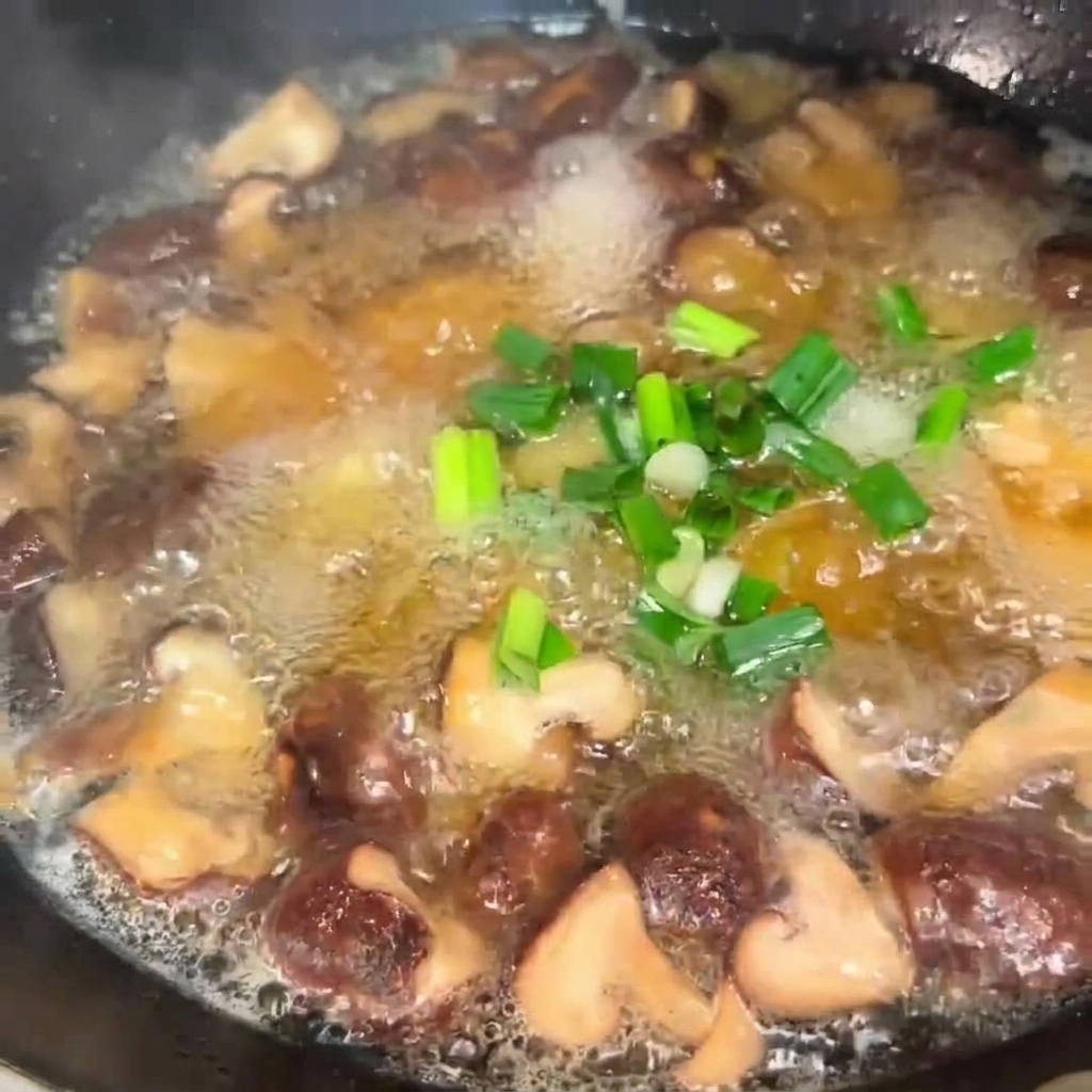 Cebollino picado siendo espolvoreado en una olla burbujeante de sopa de setas y tofu.