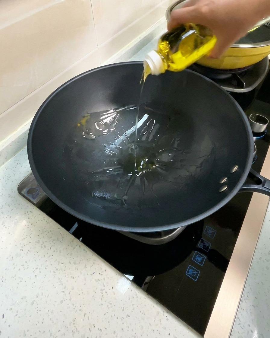 Aceite de cocina siendo vertido en un wok negro precalentado.