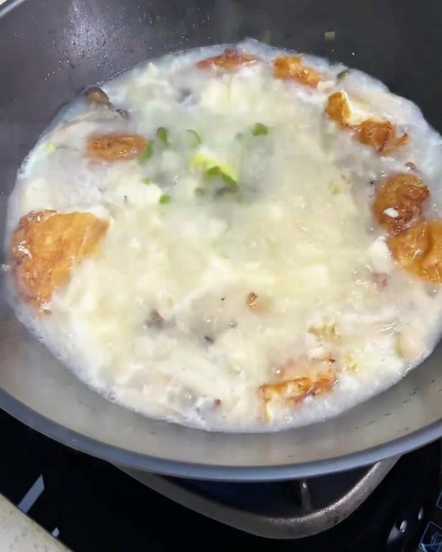 La sopa terminada de setas y tofu siendo decorada con un puñado de cebollín fresco picado.