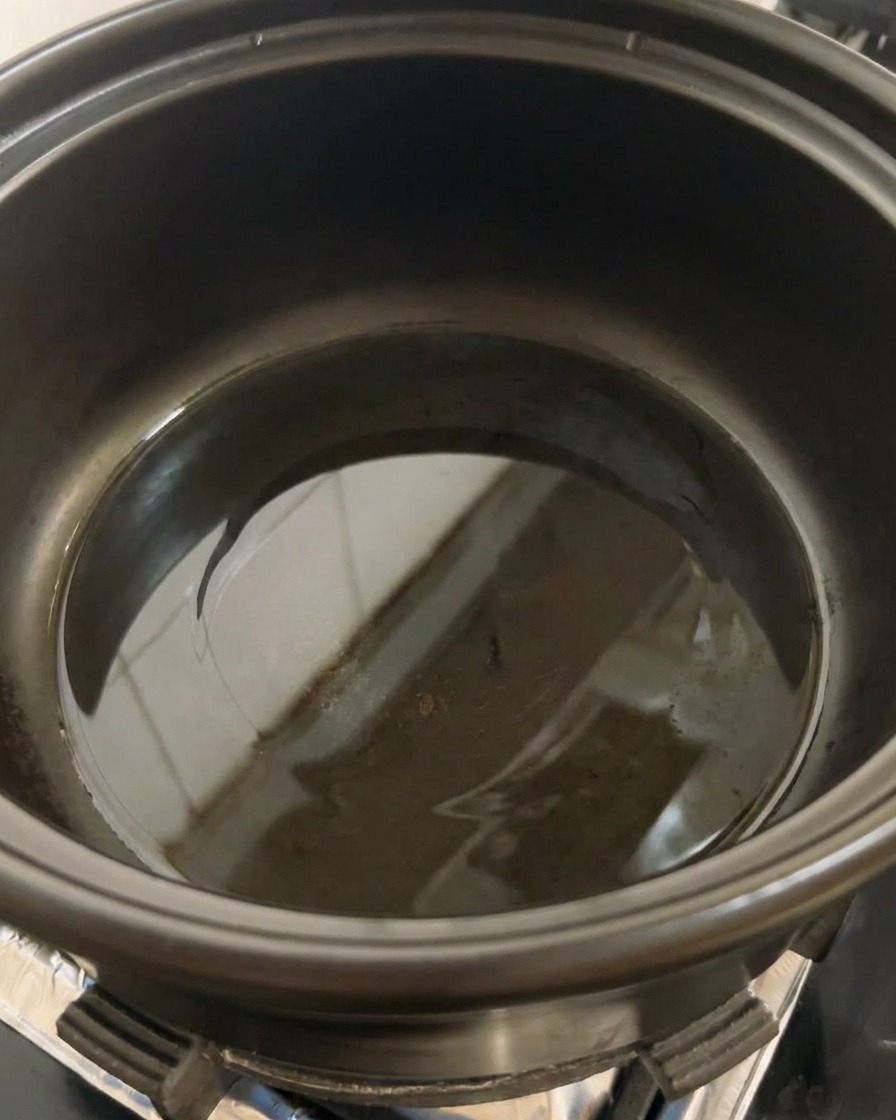 Una olla negra sobre la estufa con un poco de aceite de cocina empezando a calentarse en el fondo.