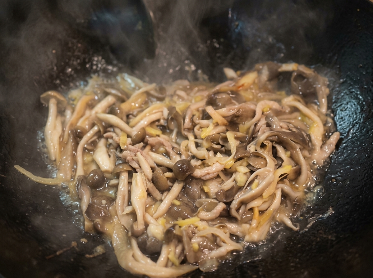 Agua hirviendo en un wok con champiñones salteados, formando un caldo ligero.