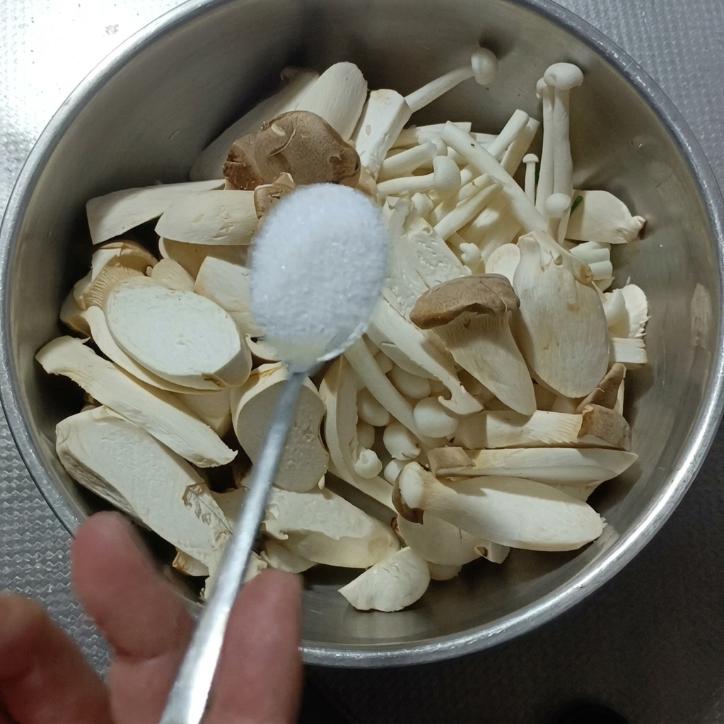 Setas eryngii y de haya siendo lavadas con sal en un bol de metal.