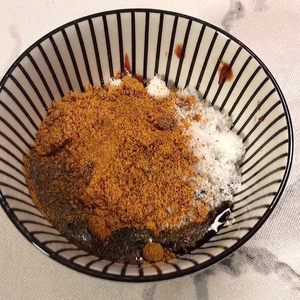 Salsa de soja clara siendo vertida en la mezcla que contiene pasta de chile, azúcar y sazonador.