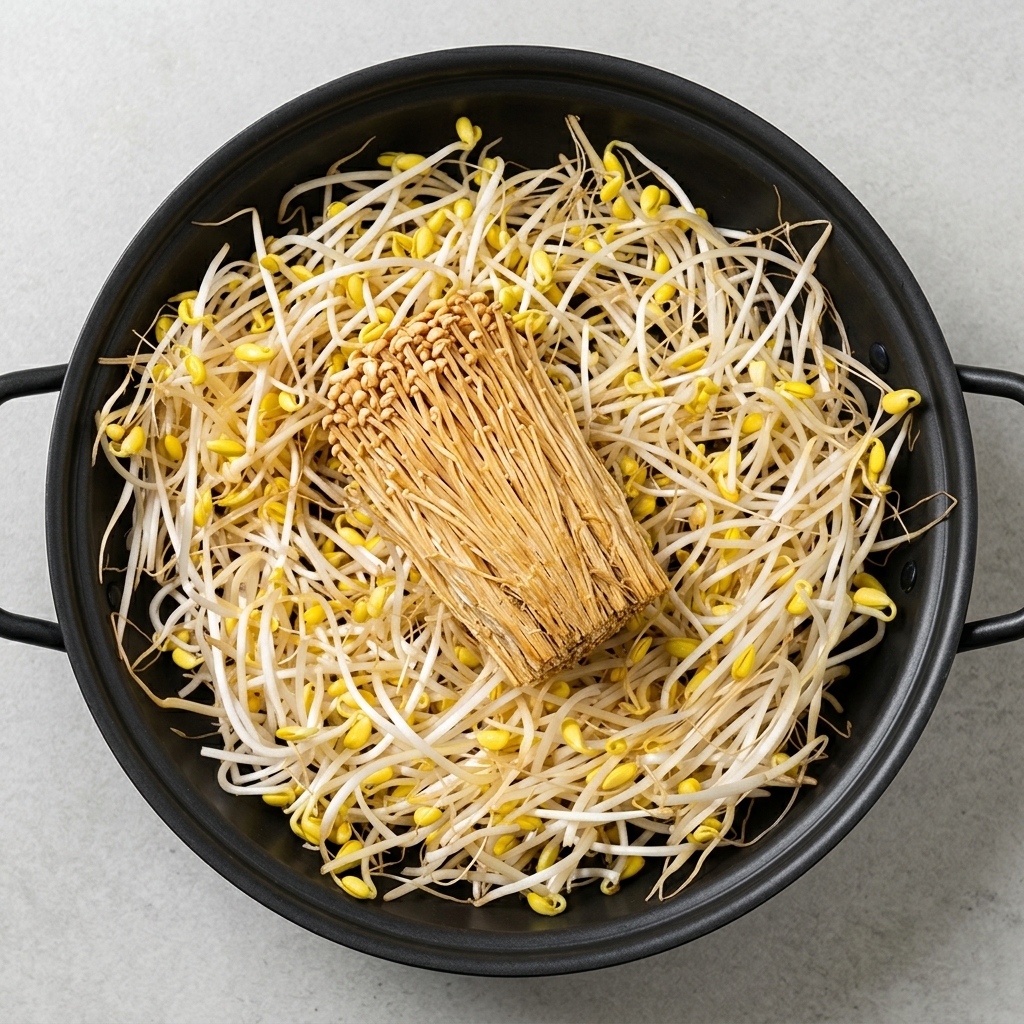 Una gran variedad de ingredientes preparados incluyendo brotes de soja, tofu, setas enoki, spam y salchichas dispuestos ordenadamente en una olla.