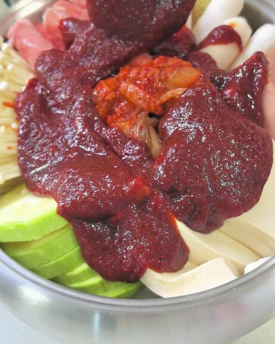 Una olla llena de ingredientes y caldo, cubierta con una tapa, hirviendo a fuego lento en la cocina.