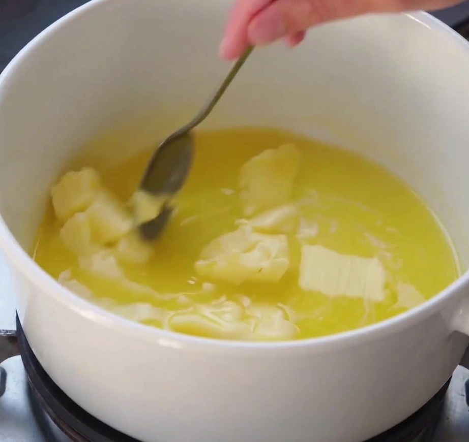 Un batidor removiendo una salsa blanca suave mientras espesa en una olla al fuego