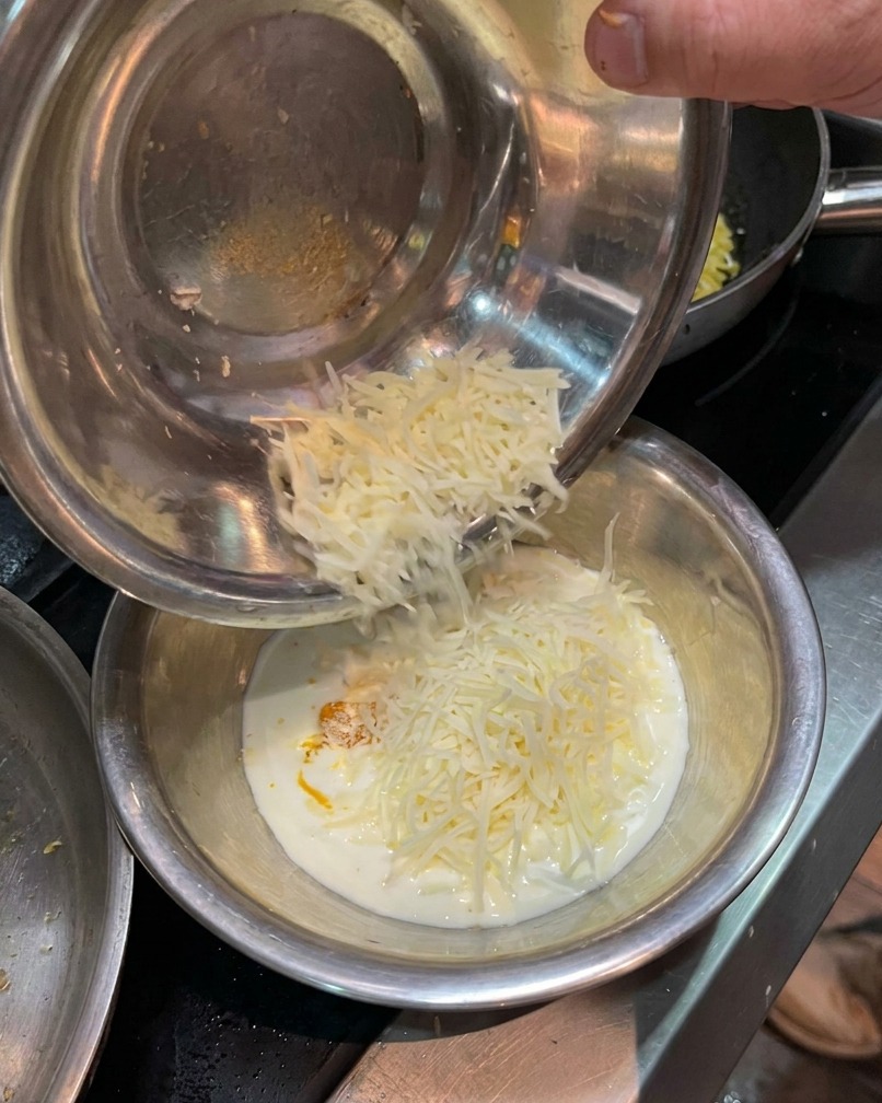 Queso parmesano rallado añadiéndose al cuenco con la yema y la nata.