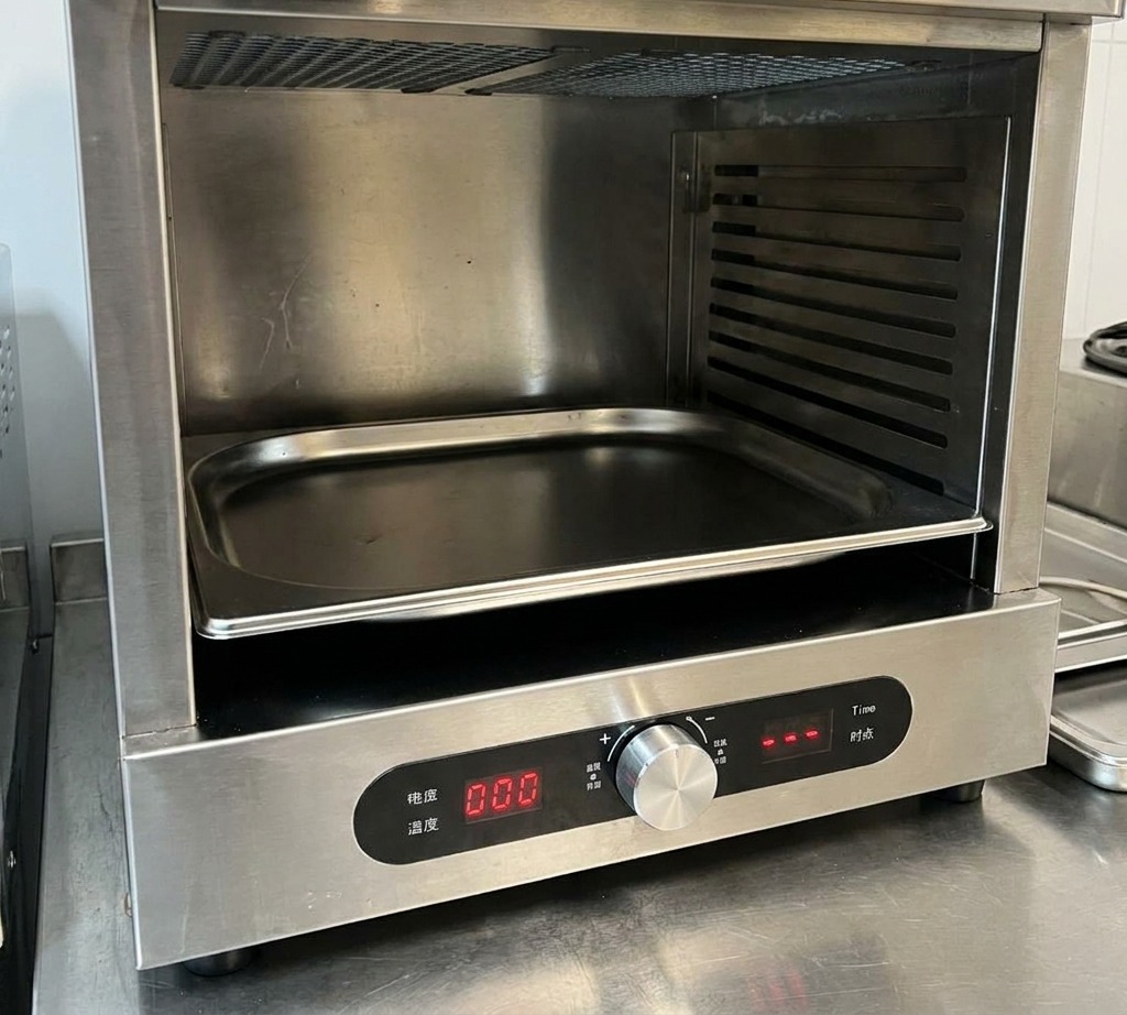 Primer plano de una mano ajustando el dial de temperatura de un horno de acero inoxidable con pantalla digital.