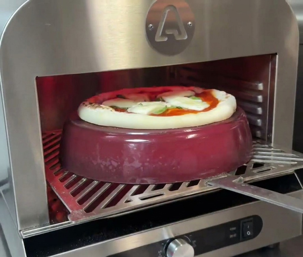 Pizza horneándose sobre una olla de hierro fundido, con el borde empezando a subir y dorarse.