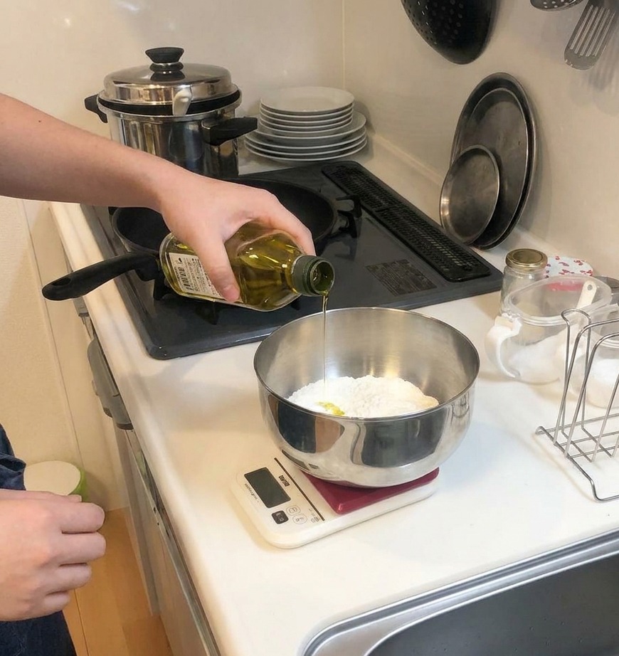 Un chorro de aceite de oliva amarillo cayendo de una botella de cristal en un bol con harina.