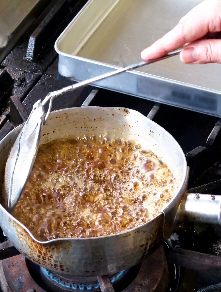 Láminas de ajo friéndose en una olla con aceite burbujeante y vapor subiendo.
