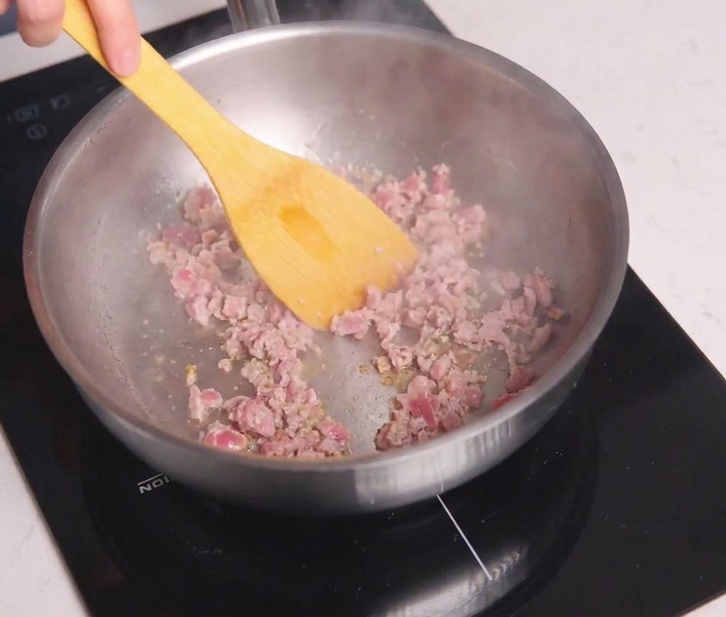 Carne picada siendo salteada en una sartén con una espátula amarilla hasta dorarse.