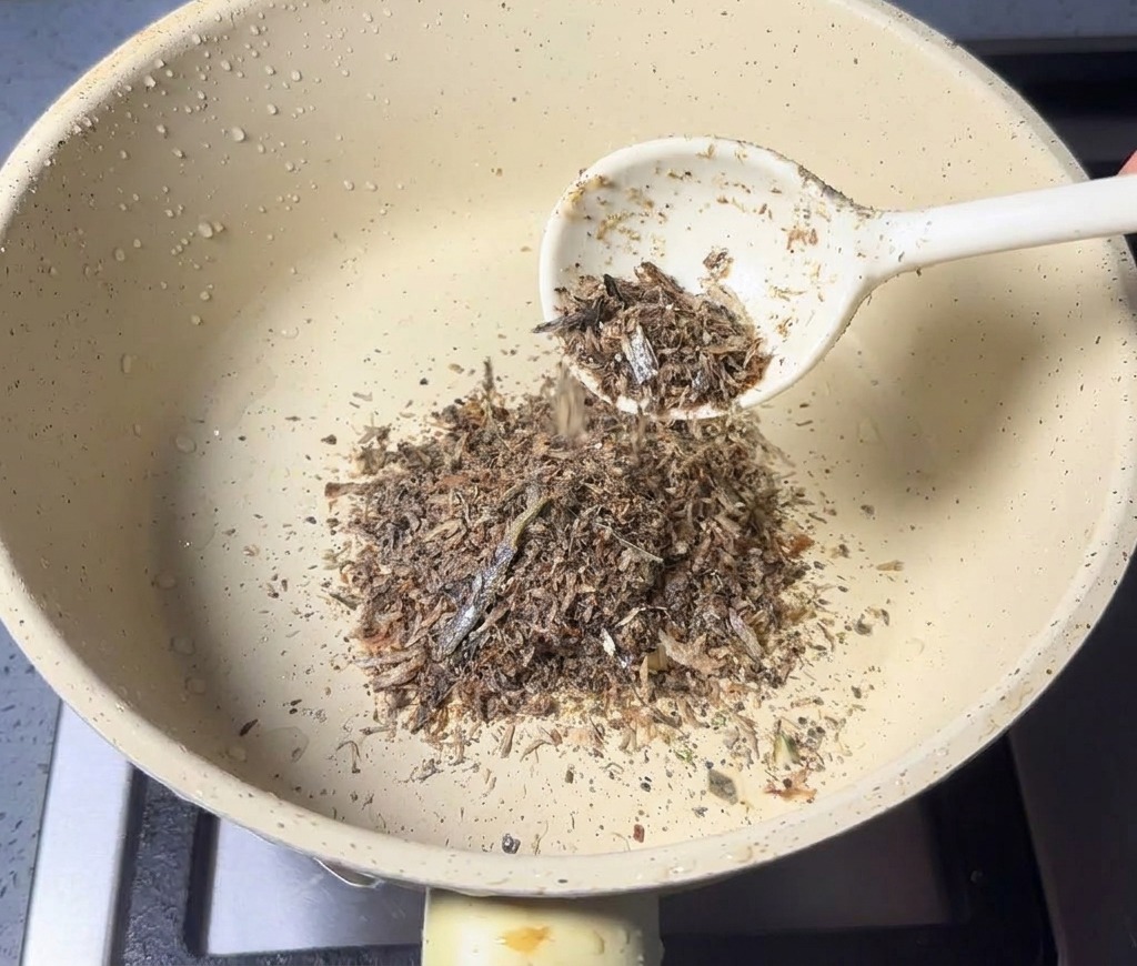 Una cucharada de polvo de marisco cayendo en una cacerola pequeña