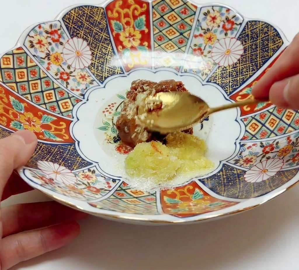Cuchara mezclando vigorosamente la pasta de miso con aceite y condimentos en un bol cerámico.