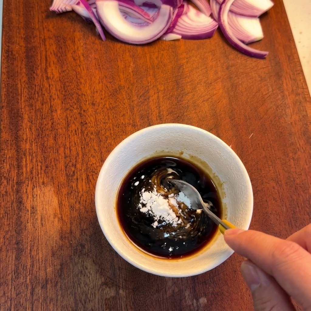 Una cuchara removiendo una salsa oscura en un cuenco para disolver polvos blancos de almidón.