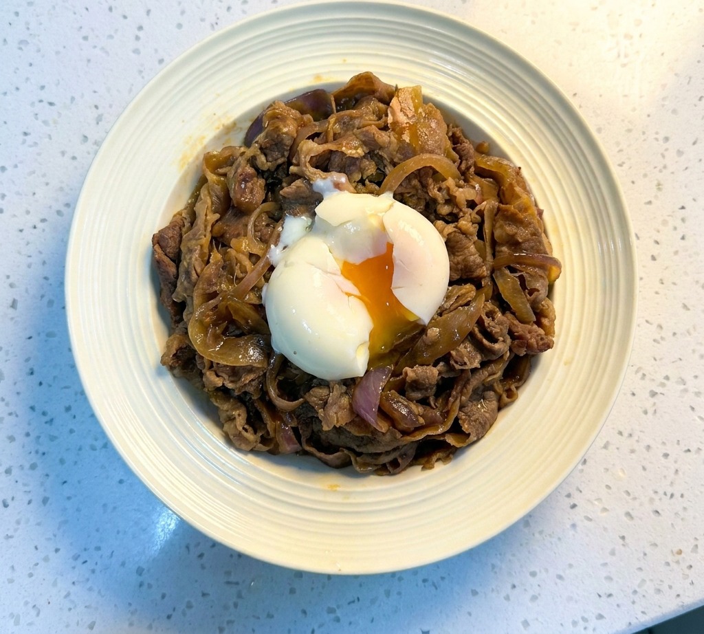 Un cuenco de Gyudon japonés coronado con un huevo onsen de yema naranja brillante.