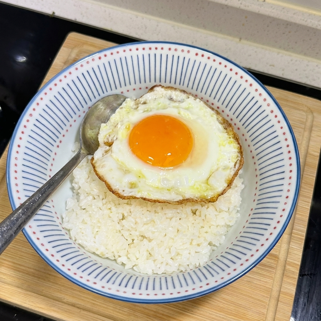 Bol de arroz blanco con un huevo frito de yema líquida y bordes crujientes en el centro.
