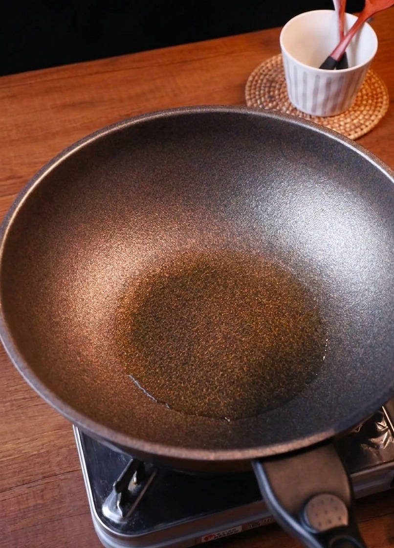 Cebolla recién cortada y una porción de kimchi picado cayendo en la sartén sazonada.