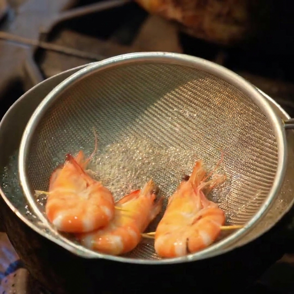 Tres gambas enteras hirviendo en un colador plano dentro de una olla con agua burbujeante.
