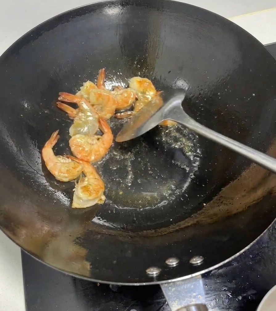 Camarones enteros volviéndose de color rosa brillante al ser salteados en un wok.