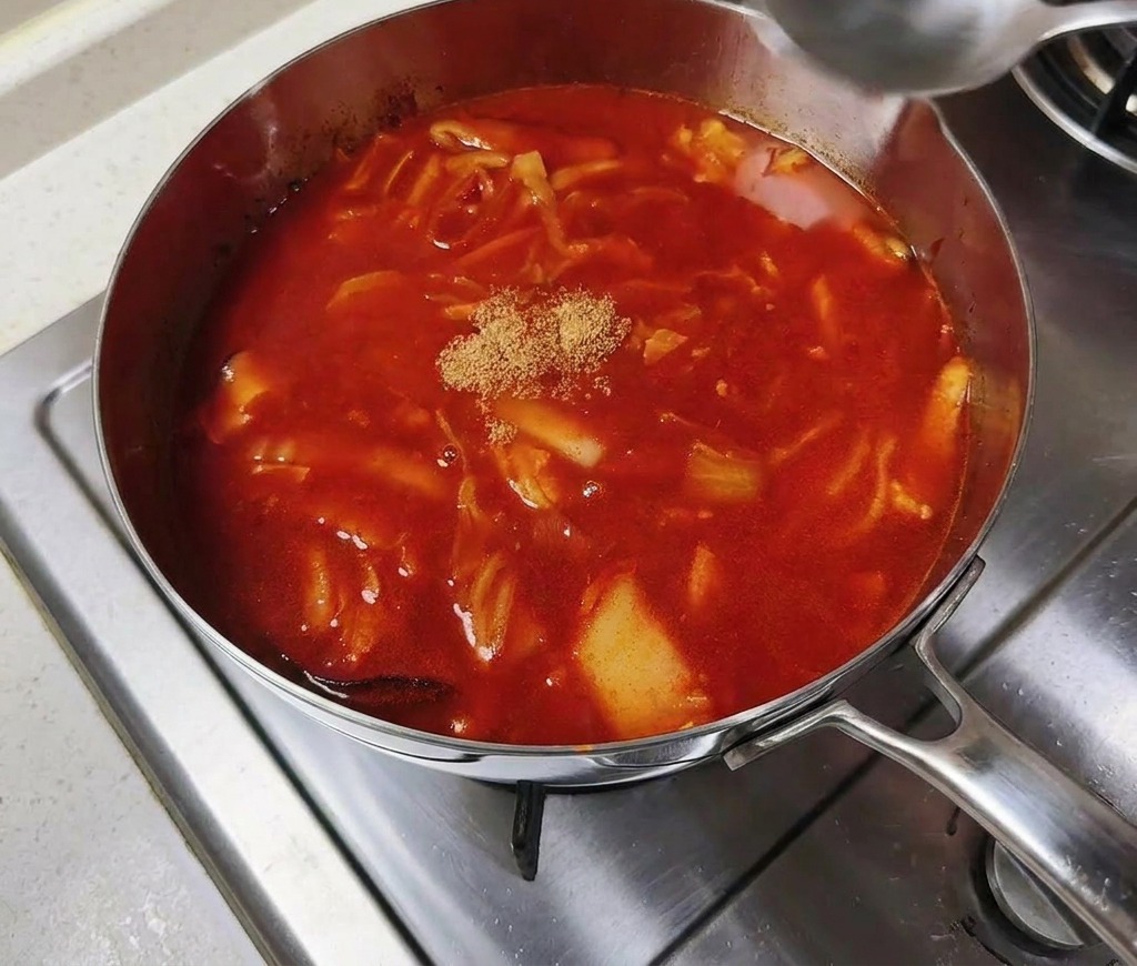 Caldo de ternera en polvo en el centro de una olla con caldo rojo picante hirviendo.