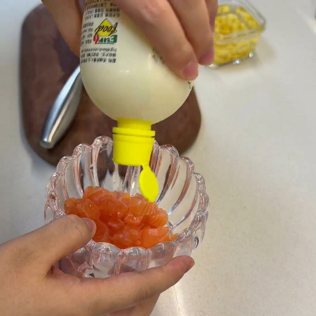 Zumo de limón fresco siendo exprimido sobre una pila de cubos de salmón crudo en un bol de cristal.