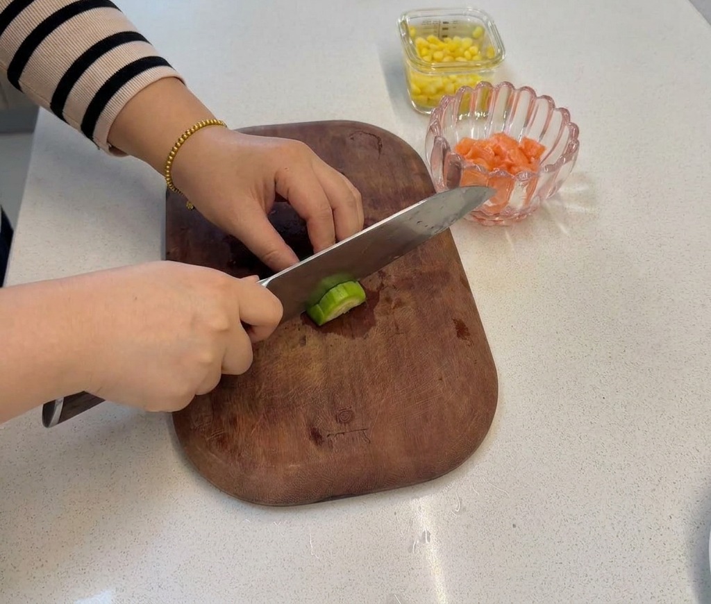 Una mano cortando el tallo de un brócoli con un cuchillo para crear ramilletes pequeños de tamaño bocado.