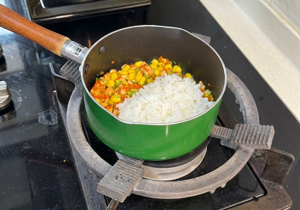 Una porción de arroz blanco al vapor sobre la colorida mezcla de salmón y vegetales en la sartén.